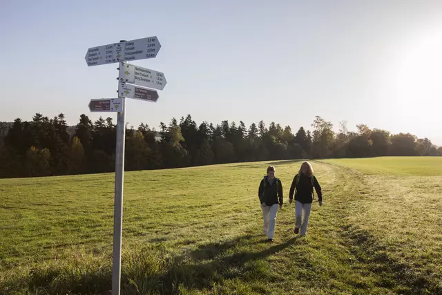 Hier sehen Sie zwei Frauen, die auf einem Weg entlangwandern.